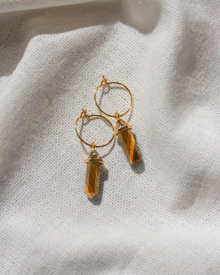 A pair of gold hoop earrings with faceted tiger's eye crystal charms.