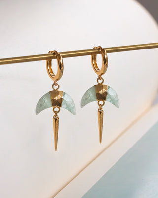 Pair of gold huggie hoop earrings with faceted Aquamarine crescent horn charm and gold spike displayed on a gold rod.