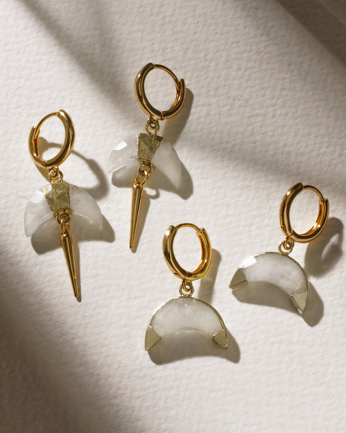 Gold huggie hoop earrings featuring a crescent horn charm in Moonstone.