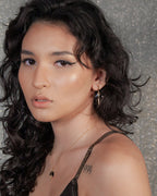 Earring with blue gemstone and gold horn charm on a woman.