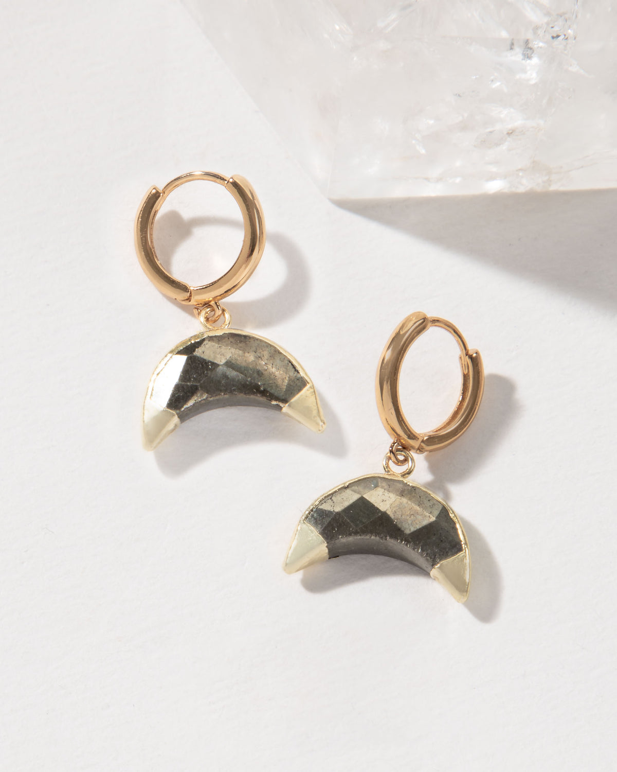 Pair of gold hoop earrings with crescent pyrite gemstones.
