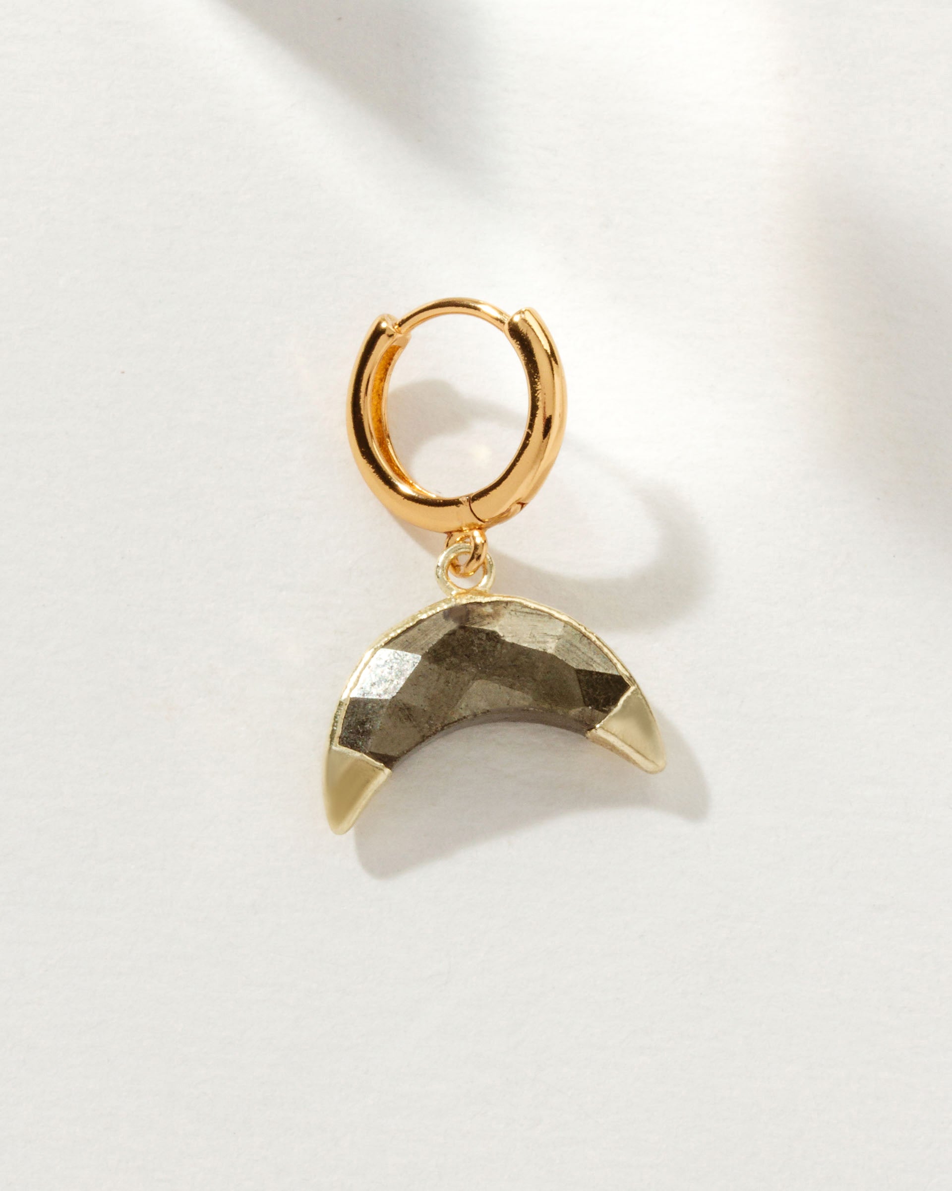 Gold huggie hoop earring with a pyrite crescent-shaped gemstone dangle.