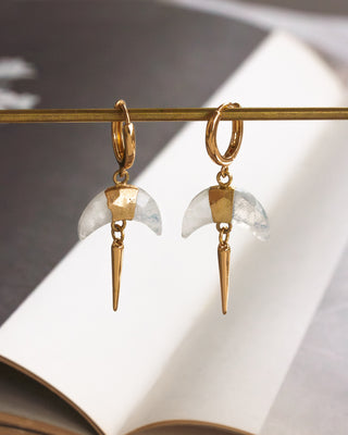 Pair of gold huggie hoop earrings with faceted Moonstpone crescent horn charm and gold spike displayed on a gold rod.