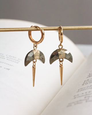 Pair of gold huggie hoop earrings with faceted Pyrite crescent horn charm and gold spike displayed on a gold rod.
