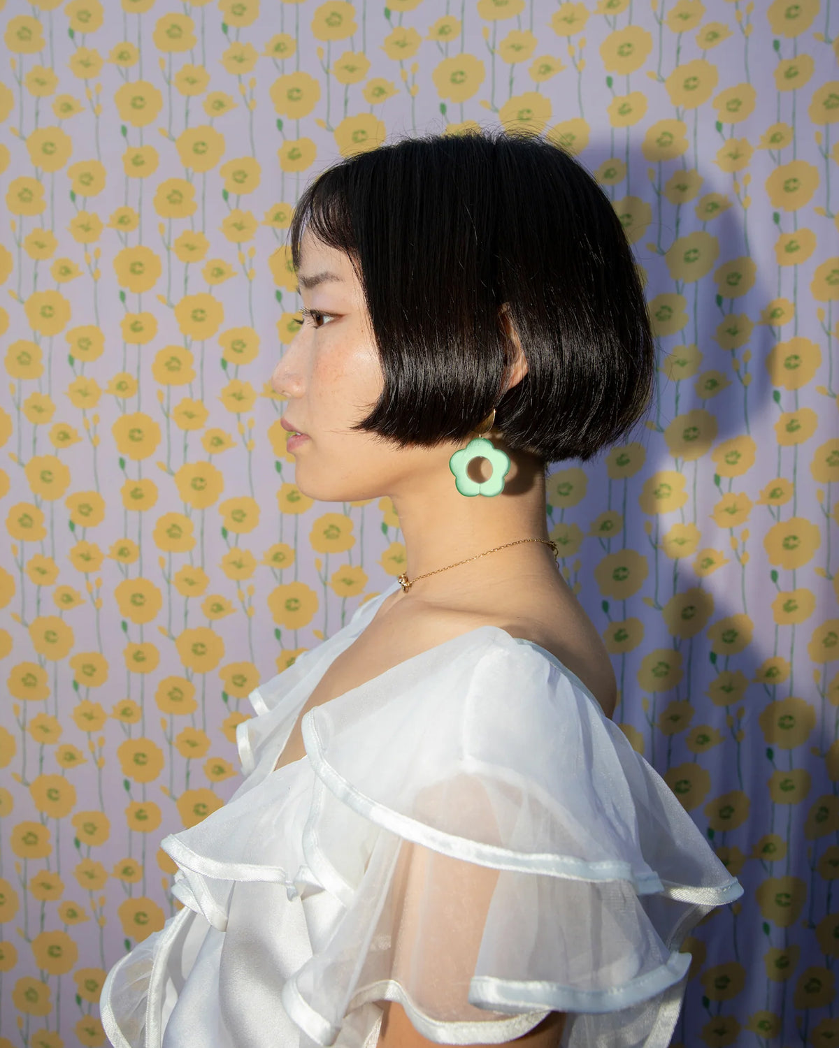 Side view of a person wearing a flower-shaped, green aventurine Oops-A-Daisy earring.