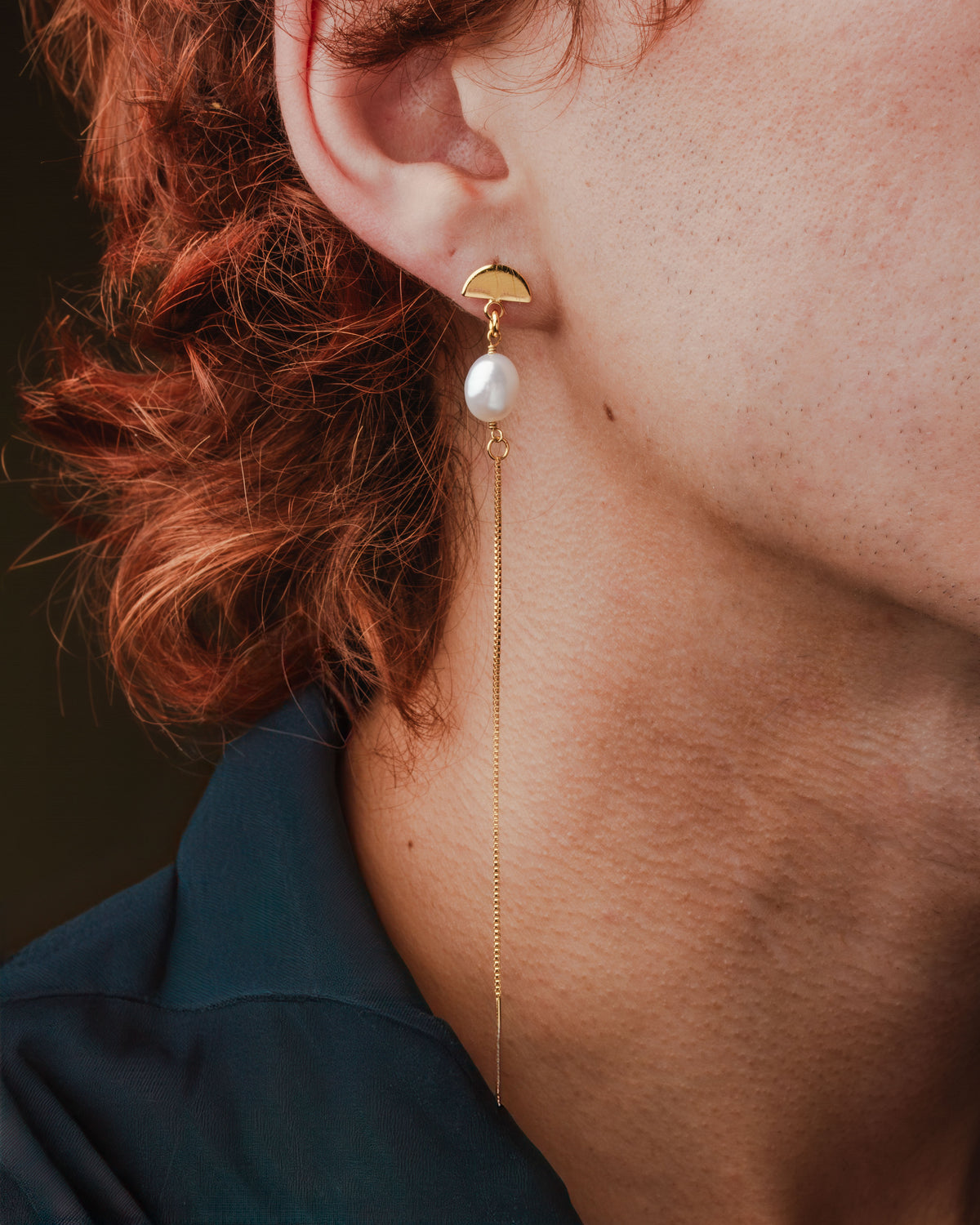 Art Deco pearl threader earring: A gold half-circle earring post with pearl and long, gold chain.