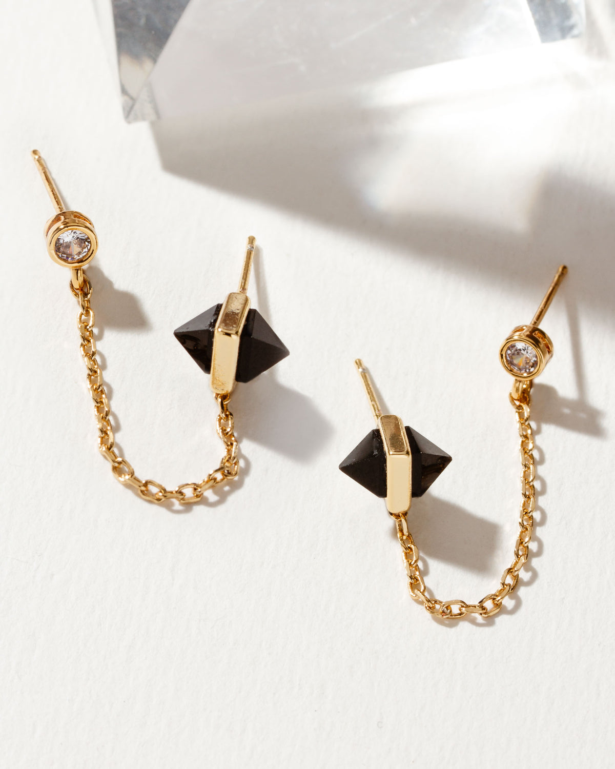 Midnight Serenade double-pierced earrings with gold chain, a crystal stud, and pyramid onyx stones.