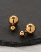 Set of gold spherical earrings on a dark slate surface