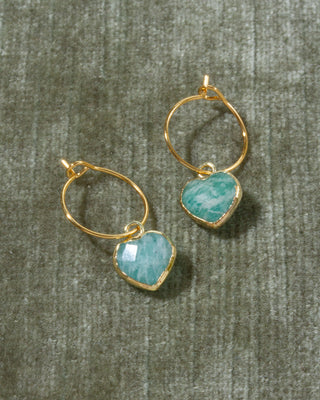 A pair of gold hoop earrings with heart-shaped light blue amazonite gemstone pendants.