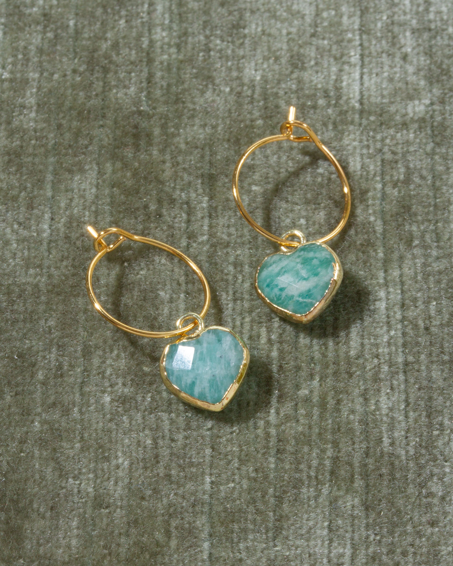 A pair of gold hoop earrings with heart-shaped light blue amazonite gemstone pendants.