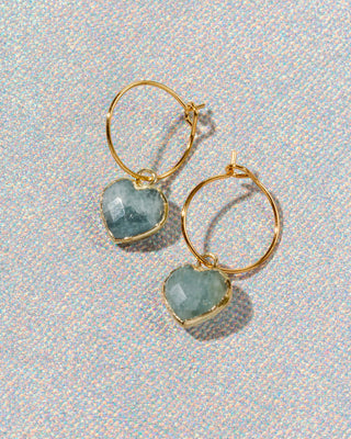 Gold hoop earrings with heart-shaped light blue aquamarine gemstone charms.