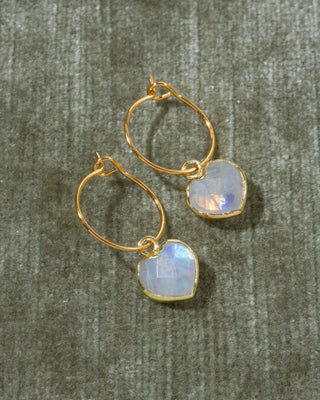 A pair of gold hoop earrings with heart-shaped iridescent moonstone drops.
