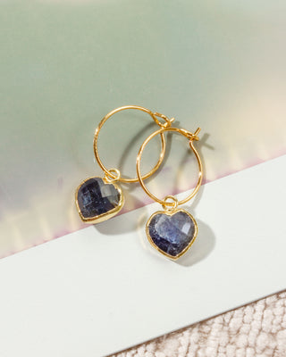 Gold hoop earrings with heart-shaped dark blue sapphire gemstone charms.