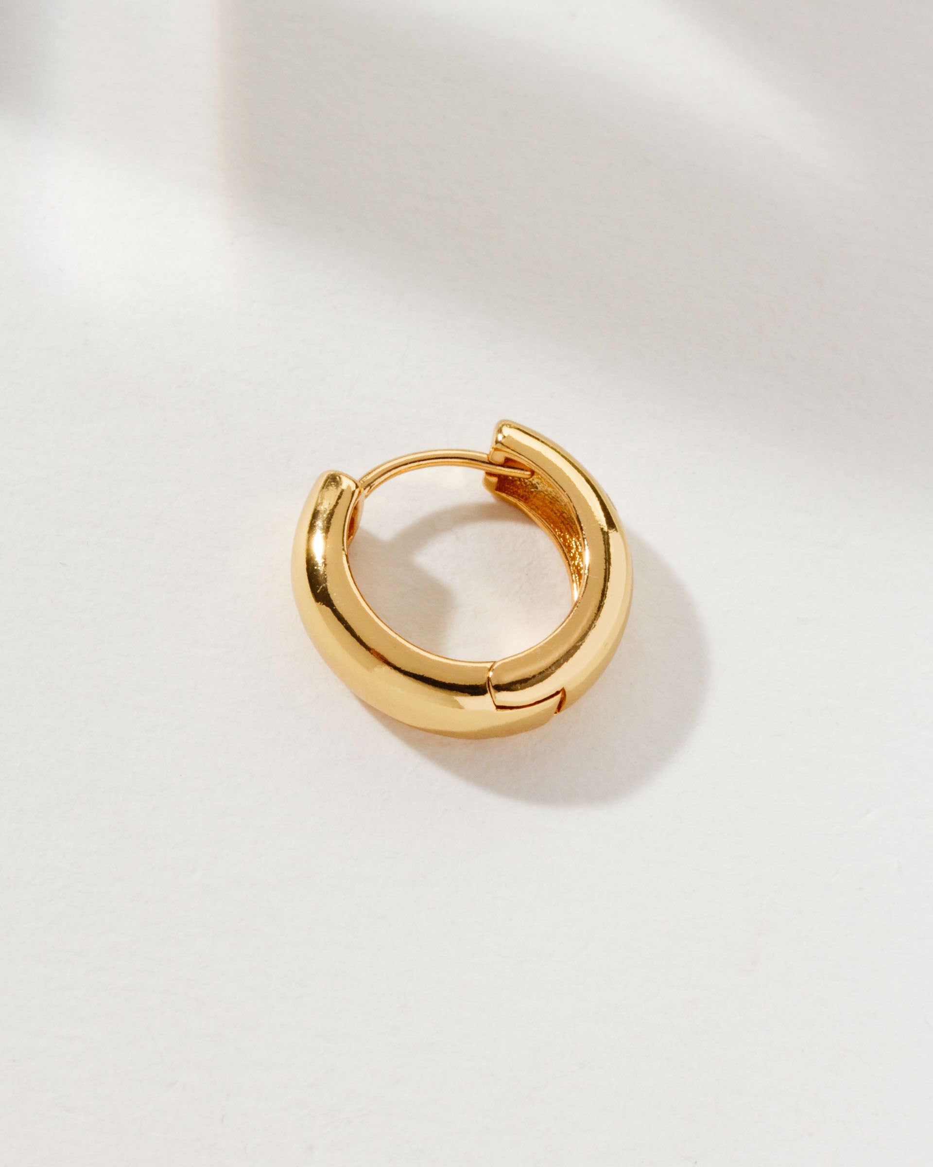 A single gold Huggie Solo Hoop Earring.