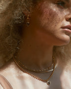 Gold huggie hoop earring with a heart charm, featuring a Plum Druzy stone.