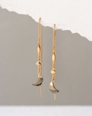 Gold earrings with geometric designs on a gray background
