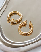 Gold hoop earrings on a reflective silver surface
