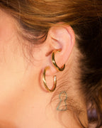 Illusive Conch Ear Cuff Adornment' pair in a polished gold finish, worn on a person's ear.