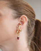 Gold Illusive Conch Ear Cuff adornment with dangling, faceted ruby gemstone charm, styled on an ear.