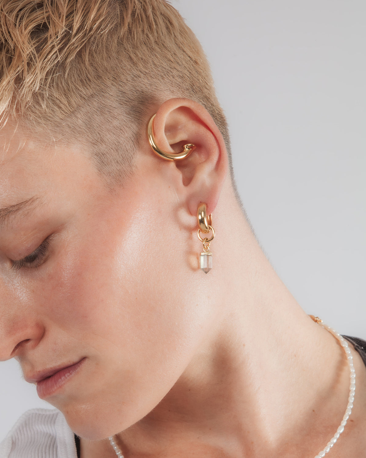 Model wearing earring cuff and charm hoops