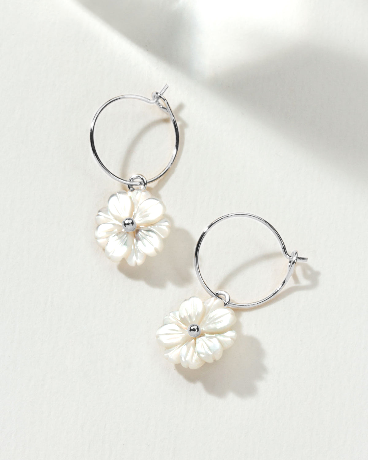 A pair of Blooming Hoop Earrings Silver, featuring delicate mother of pearl daisies.