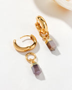 Gold huggie hoop earring with a coffee moonstone charm displayed on a white surface.