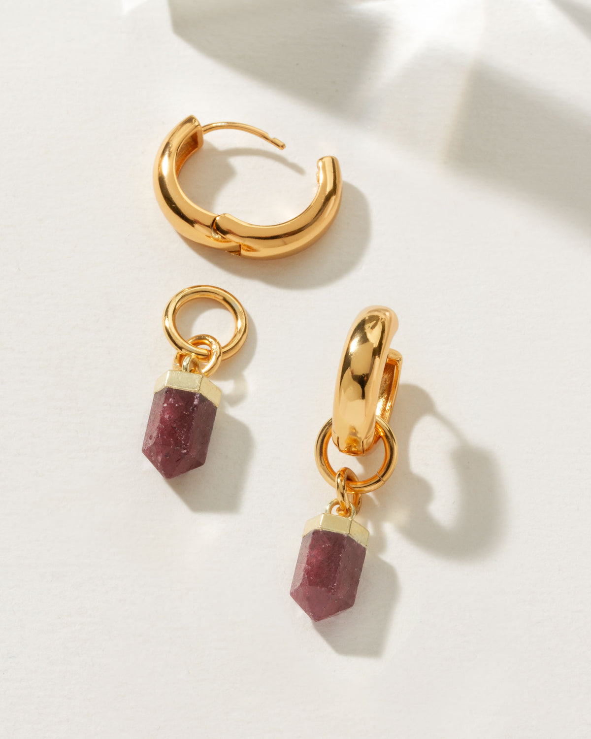 Gold huggie hoop earrings with a removable ruby gemstone point charm.