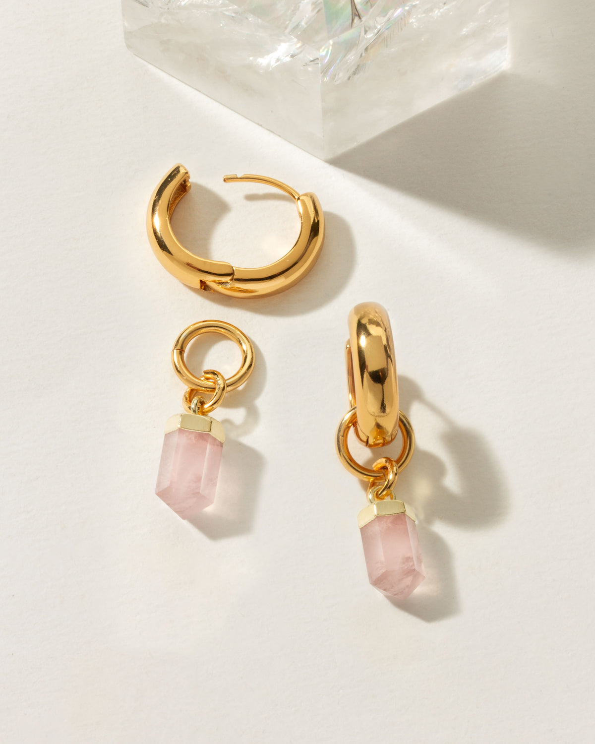 Gold huggie hoop earrings with removable pink Rose Quartz gemstone charms.