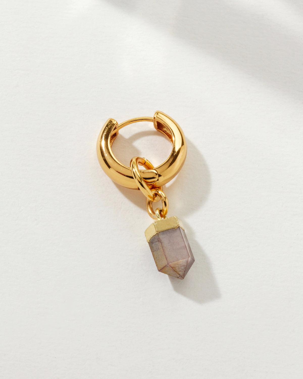 Gold huggie hoop earring with a detachable light purple spearhead charm.