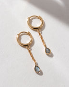 Gold huggie hoop earrings with a chain and Labradorite charm.