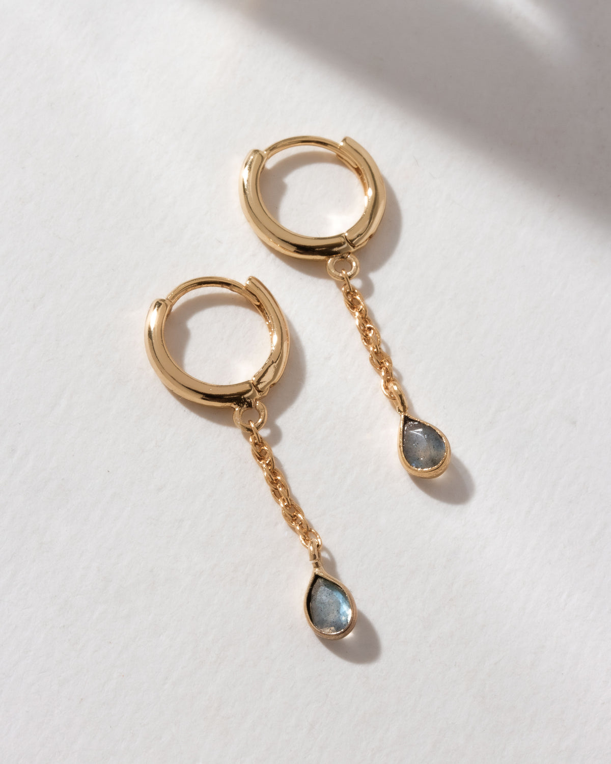 Gold huggie hoop earrings with a chain and Labradorite charm.