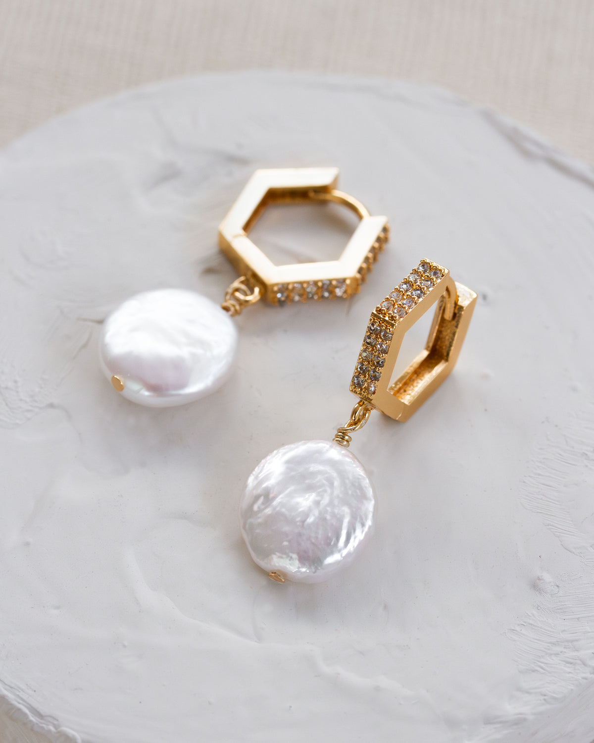 Pair of geometric gold earrings with cz elements and mother of pearl rounded drop charms.