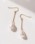Two Ocean Sway Pearl Drop Earrings with gold chain on a white background.