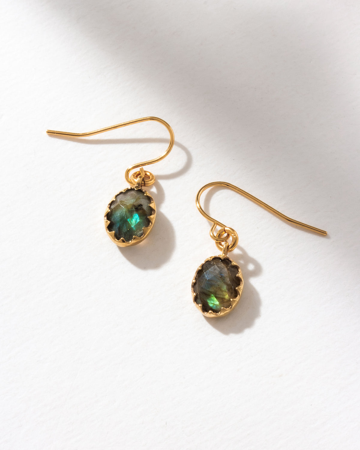 Two Neptune's Orbit earrings with faceted labradorite gems and gold hooks are