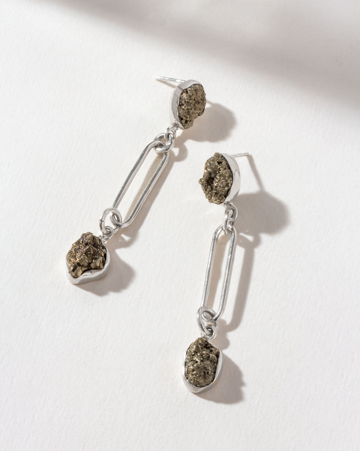 Sterling silver post earrings featuring raw pyrite stones hung from bold paperclip chain links.