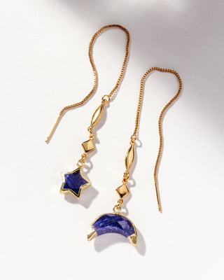 Sapphire gemstone gold threader earrings one with star charm and the other with moon charm on a white background.