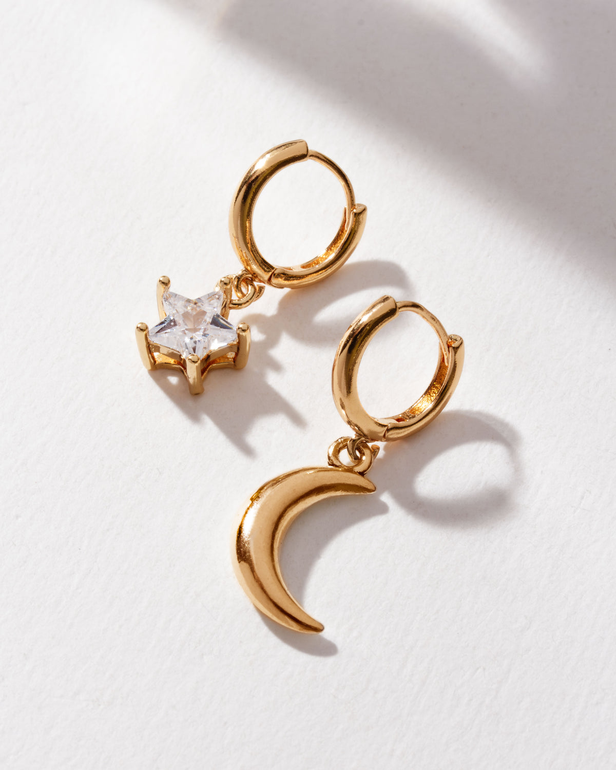 Pair of mismatched gold hoops, one with CZ star and the other with crescent moon design