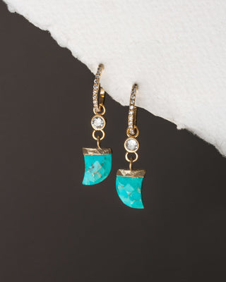 Turquoise earrings with gold accents on a dark surface