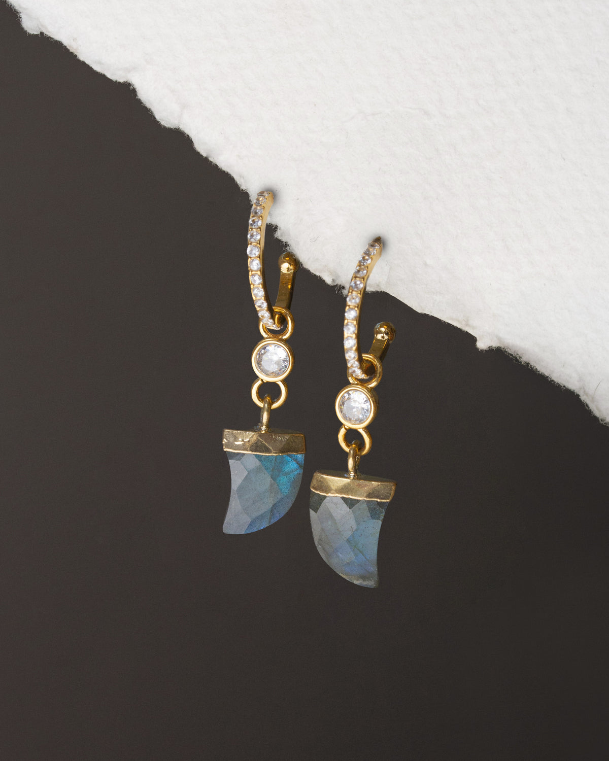 Gold earrings with blue stone drops on a black and white background