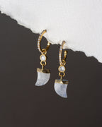 Gold and moonstone earrings on a dark surface with white stone