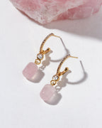 Gold and cz hoop earrings with pink rose quartz stones on a light background