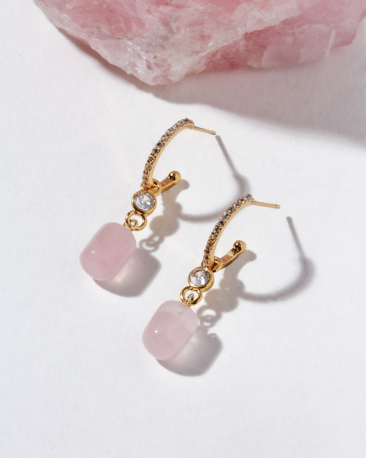 Gold and cz hoop earrings with pink rose quartz stones on a light background