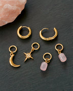 Gold hoop earrings with charms on a dark surface