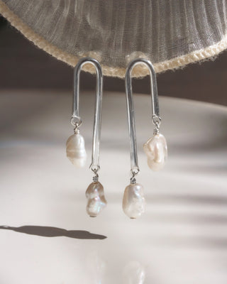 Pearl drop earrings on a neutral background