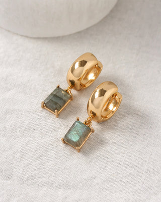 Gold hoop earrings with rectangle labradorite gemstones on a light background