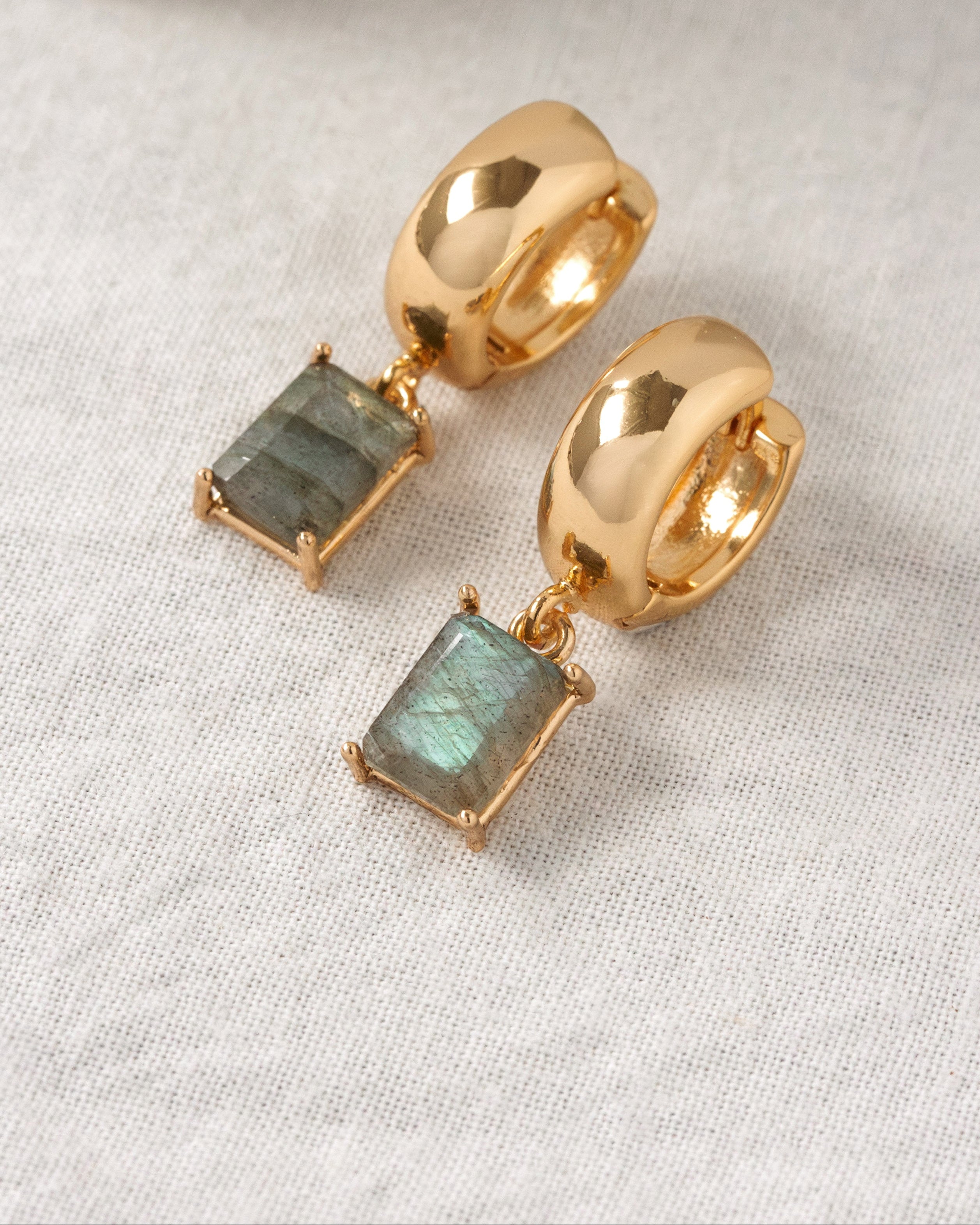 Gold hoop earrings with rectangle labradorite gemstones on a light background