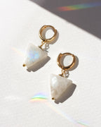 Pair of earrings with gold hoops and moonstone gemstones on a white background