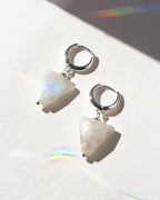 Pair of earrings with white stone and silver hoop design on a light background