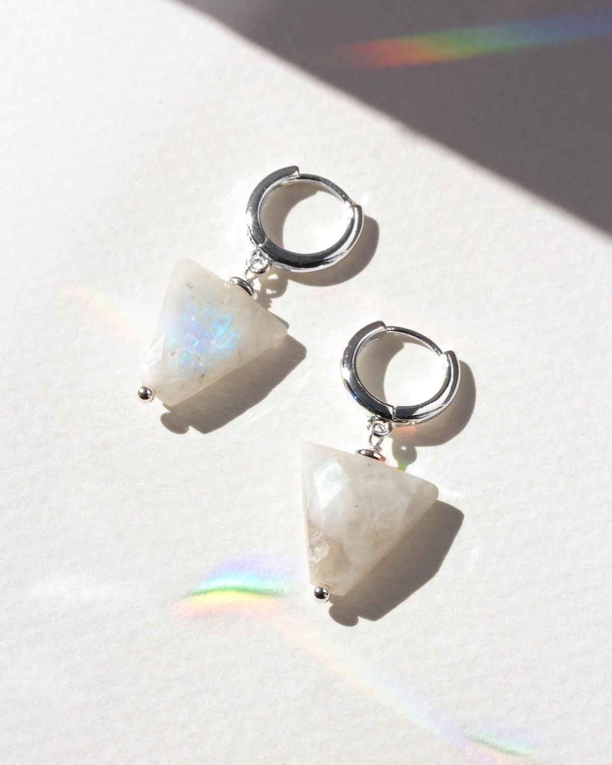 Pair of earrings with white stone and silver hoop design on a light background