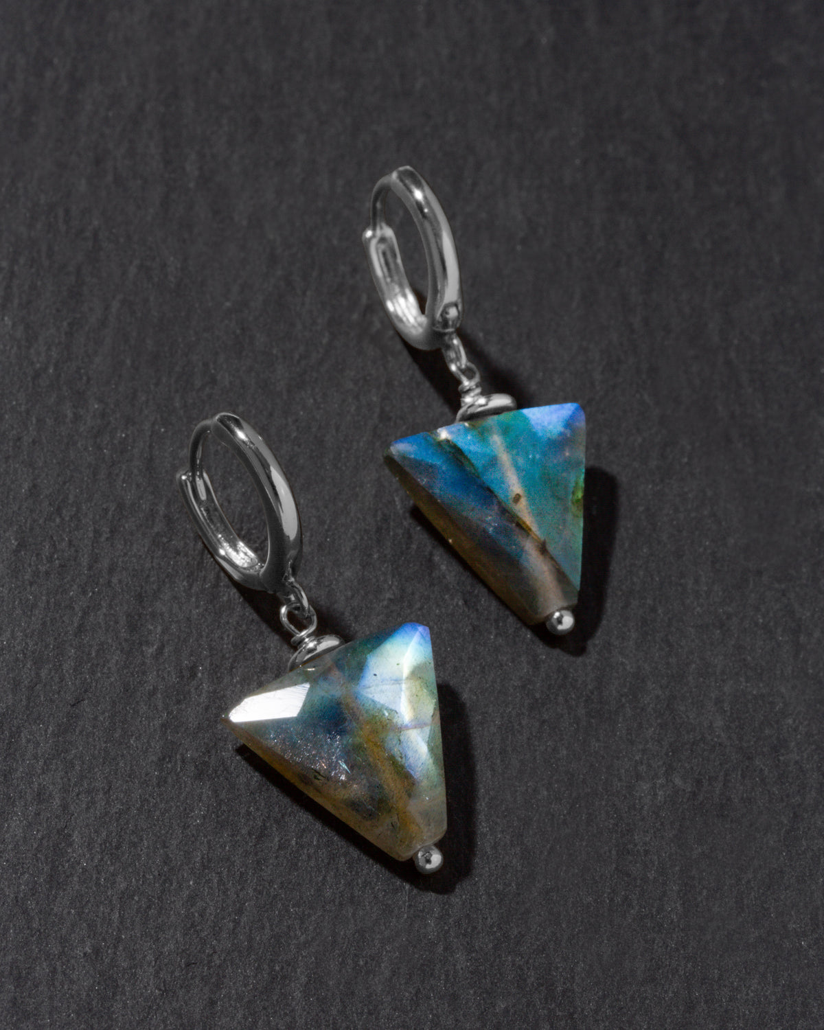 Pair of triangular labradorite earrings on a dark gray background